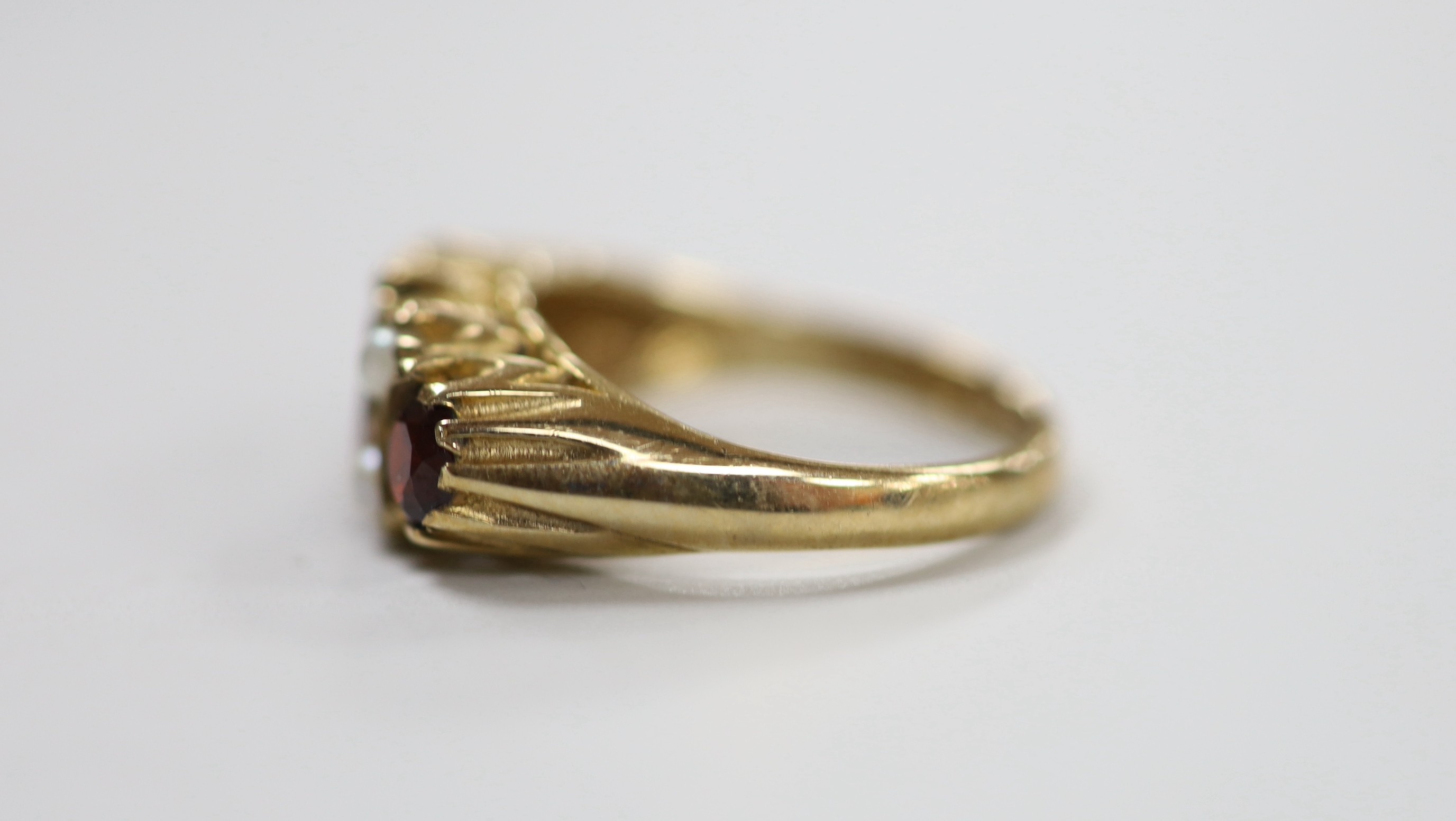 A 1970's 9ct gold, three stone garnet and four stone split pearl set half hoop ring, size K/L, gross weight 3.6 grams.